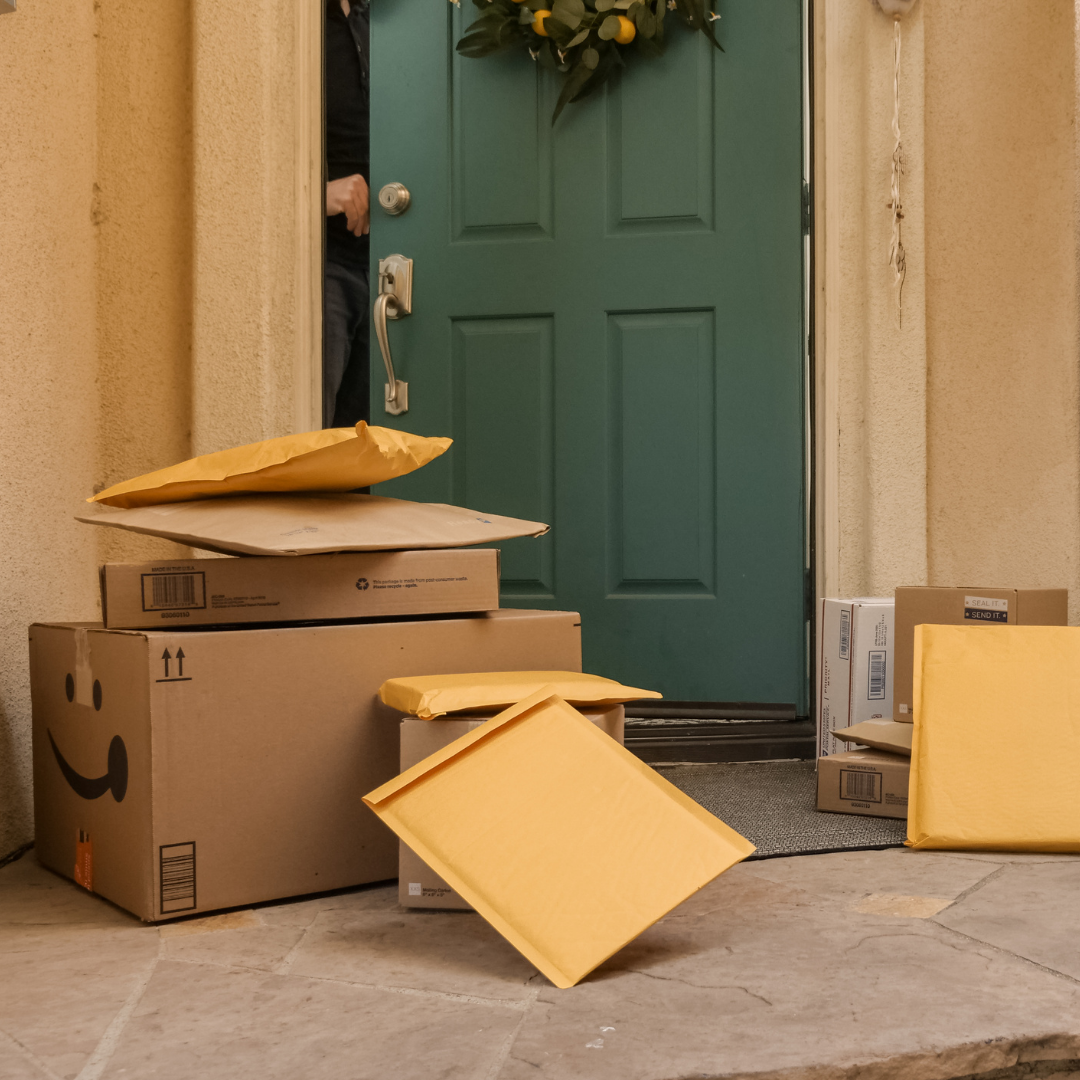 Multiple mail packages are waiting outside the front door of a home.