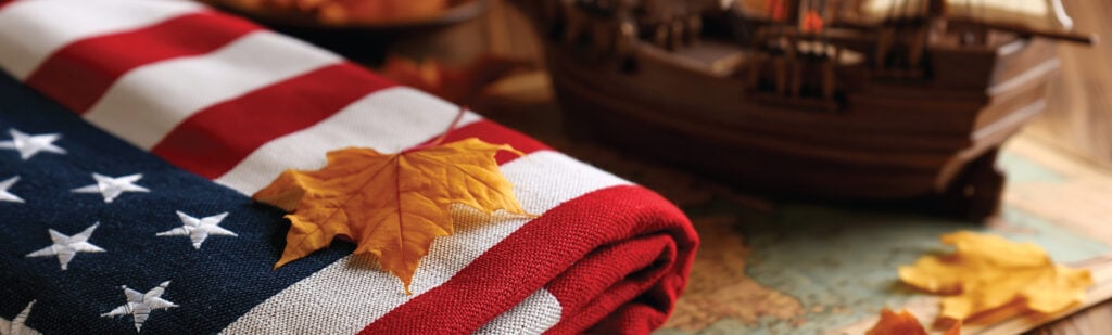 A folded American flag rests atop a map with scattered golden leaves on top of everything.
