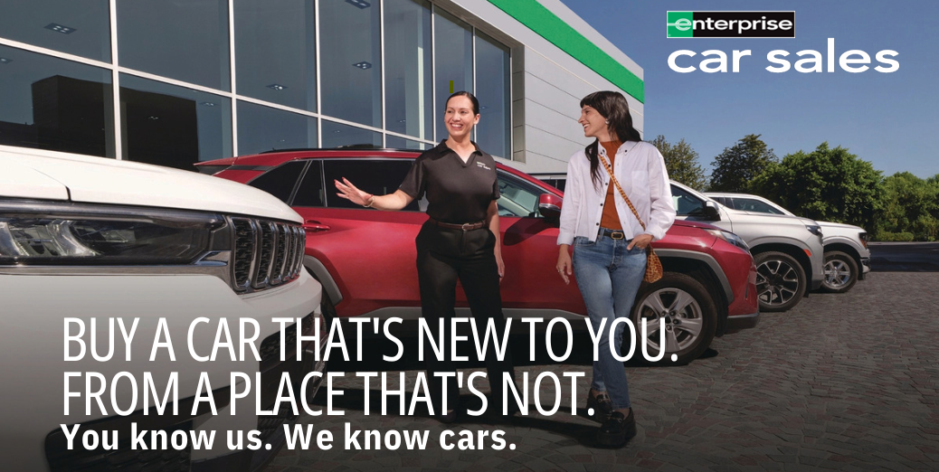 An Enterprise Car Sales person shows off a car on their lot to a customer.